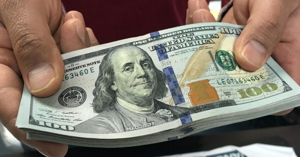 hands holding a stack of 100 dollar bills