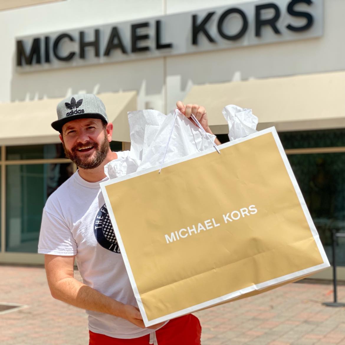 man holding a large Michael Kors bag