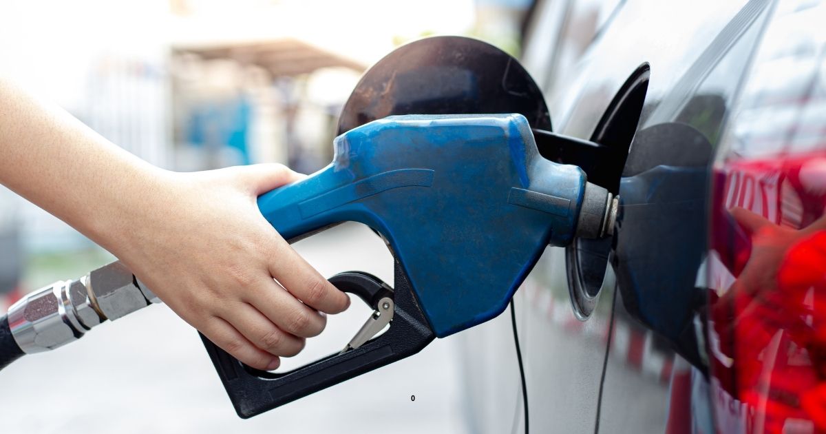 hand holding gas nozzle filling up car