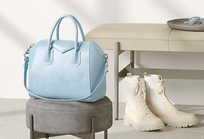 purse sitting on a stool next to a bench with boots by the bench