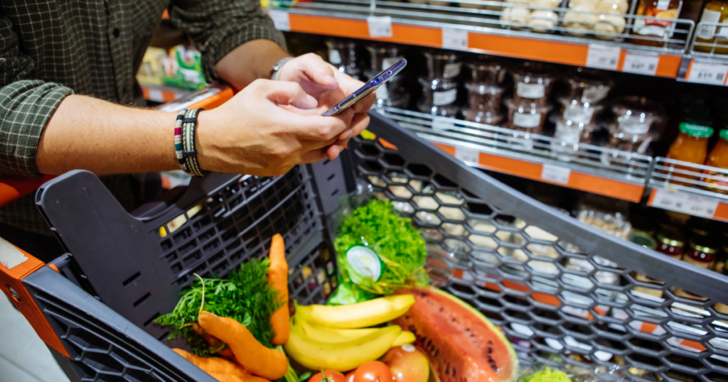 man's hands using phone in grocery store