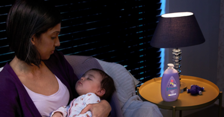 woman holding baby next to johnsons bedtime wash on table
