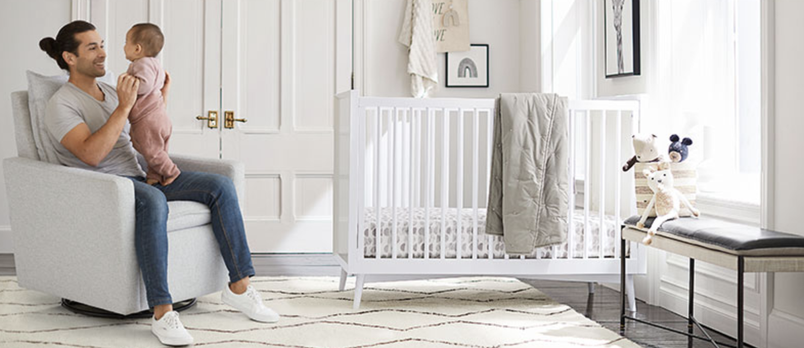 man holding a baby while sitting in a chair in a nursery
