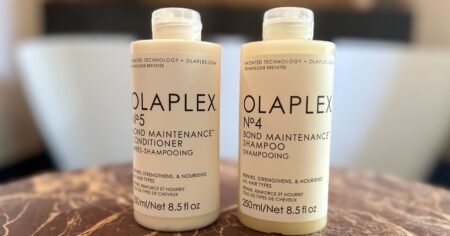 two bottles of Olaplex in front of a bathtub