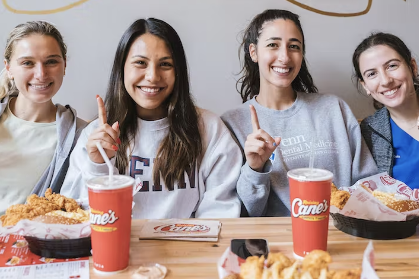 four women sitting at a table with Raising Cane's food