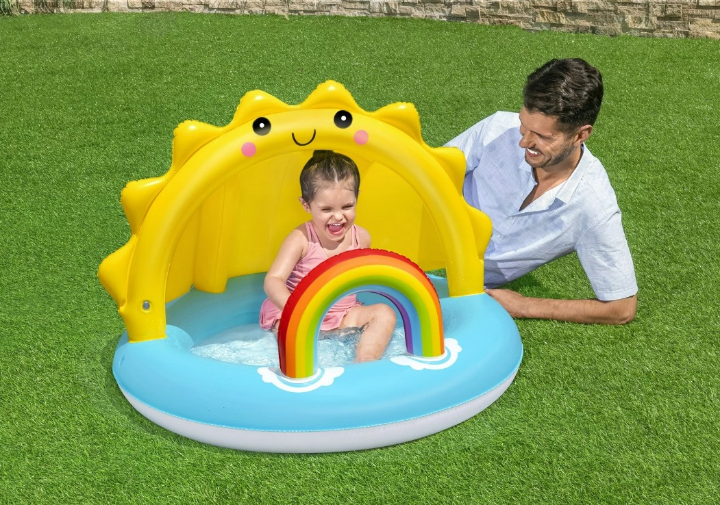 girl playing in a small pool and a man sitting next to it