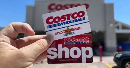 costco membership card held in a hand outside of a costco store