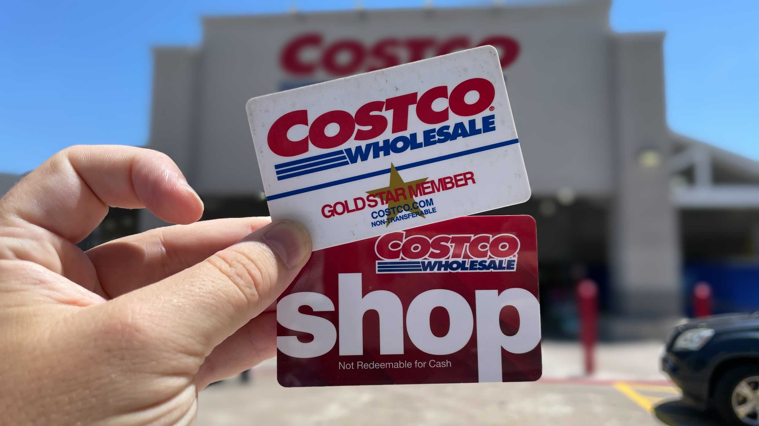 costco membership card held in a hand outside of a costco store