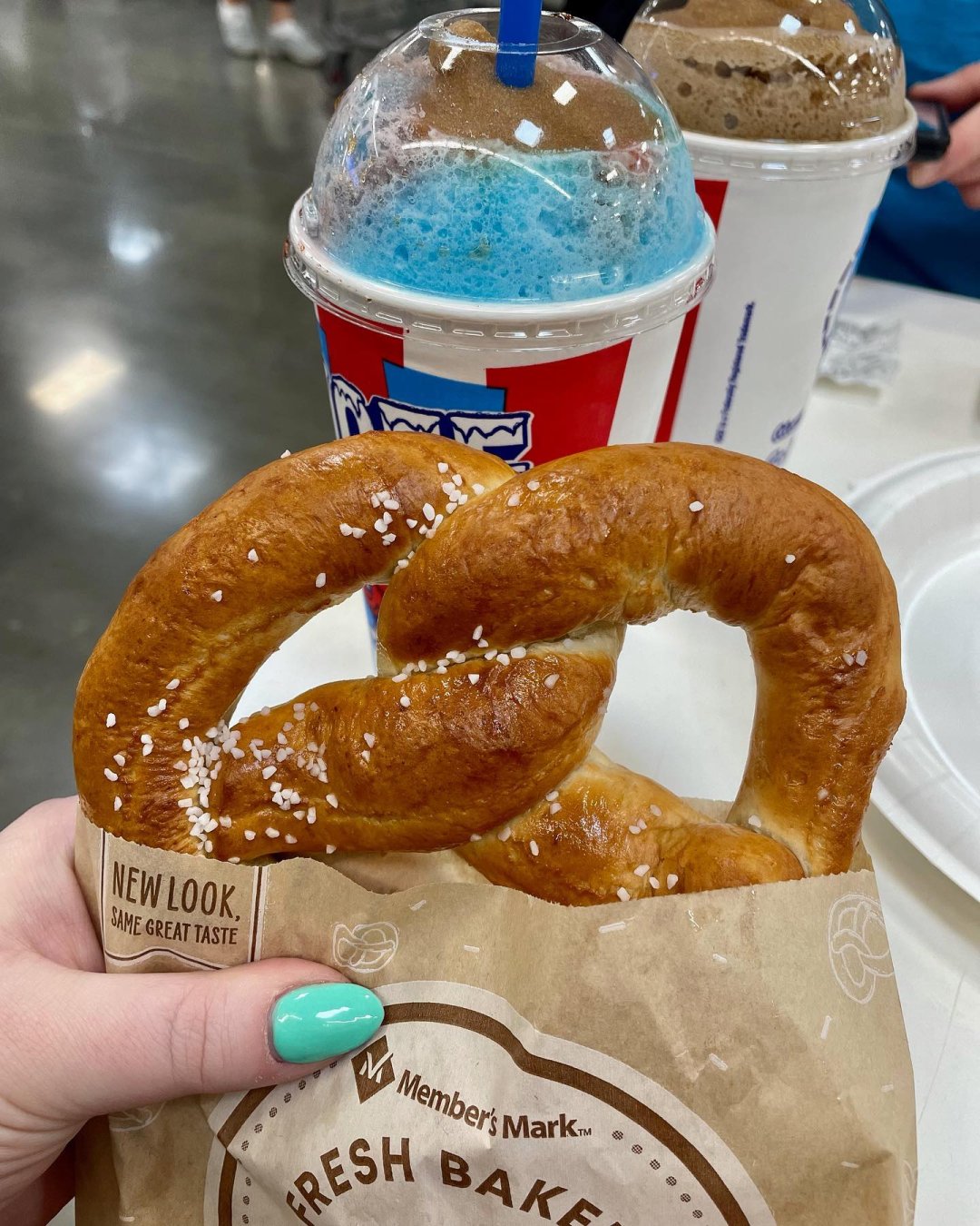 hand holding a pretzel in front of two ICEE's