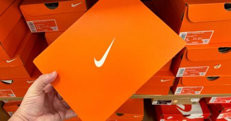 Person Holding Orange Nike Shoe Box in Nike Store with New Nike Shoe Drops and Clearance Deals