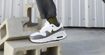 Person wearing Gray & White Nike Air Max Shoe on Sale Stands on Cinder Block