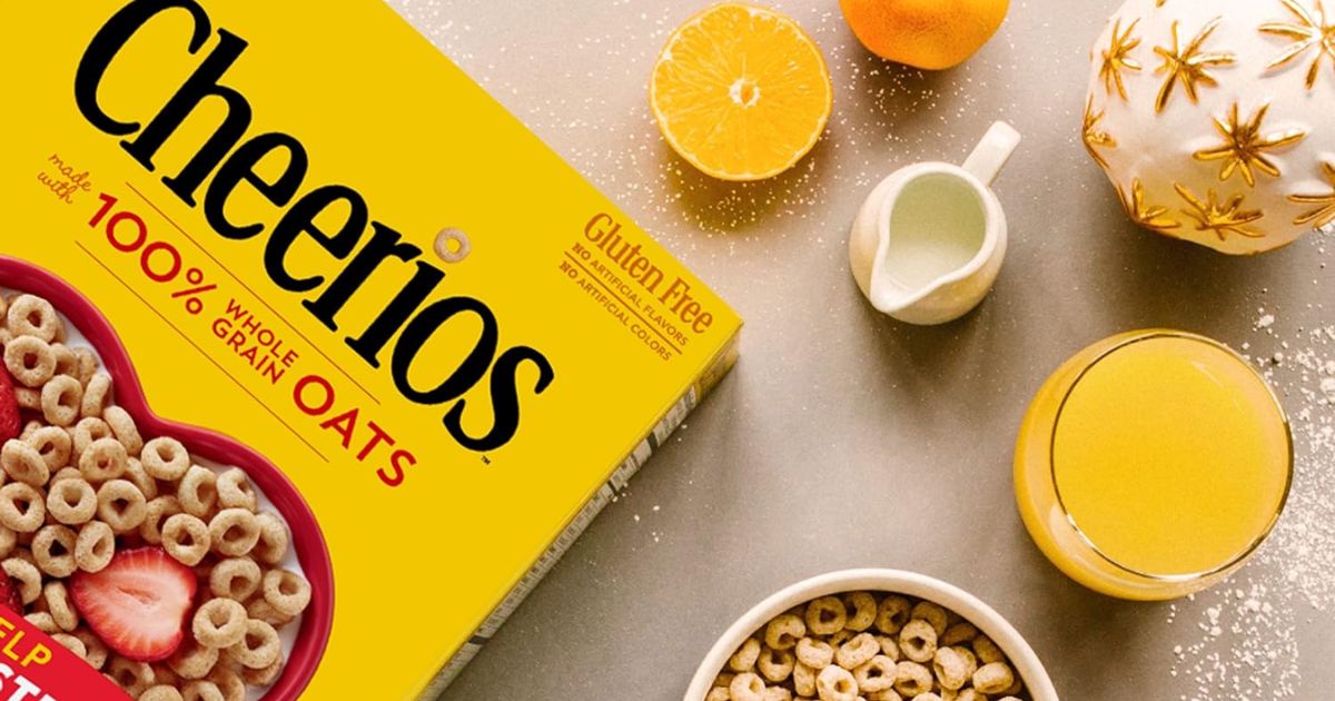 Cheerios Box of Cheerios laying on a table with a bowl of Cheerios next to it