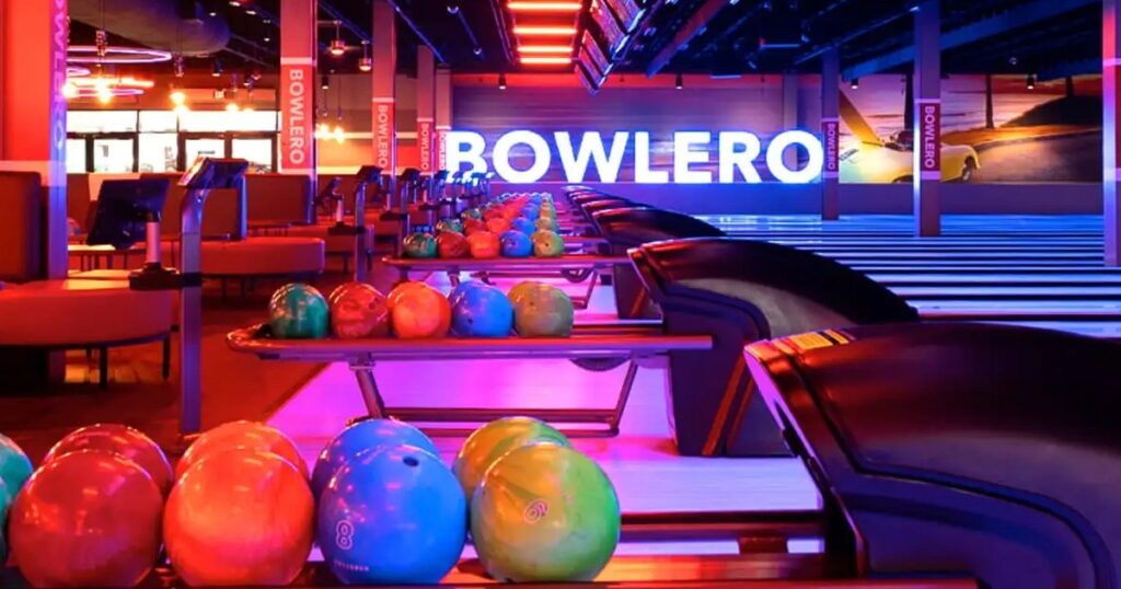 bowling lanes with bowling balls on the return and a large bowlero sign