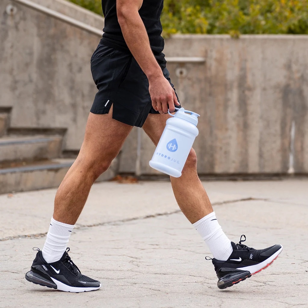 person walking and holding a HydroJug water bottle