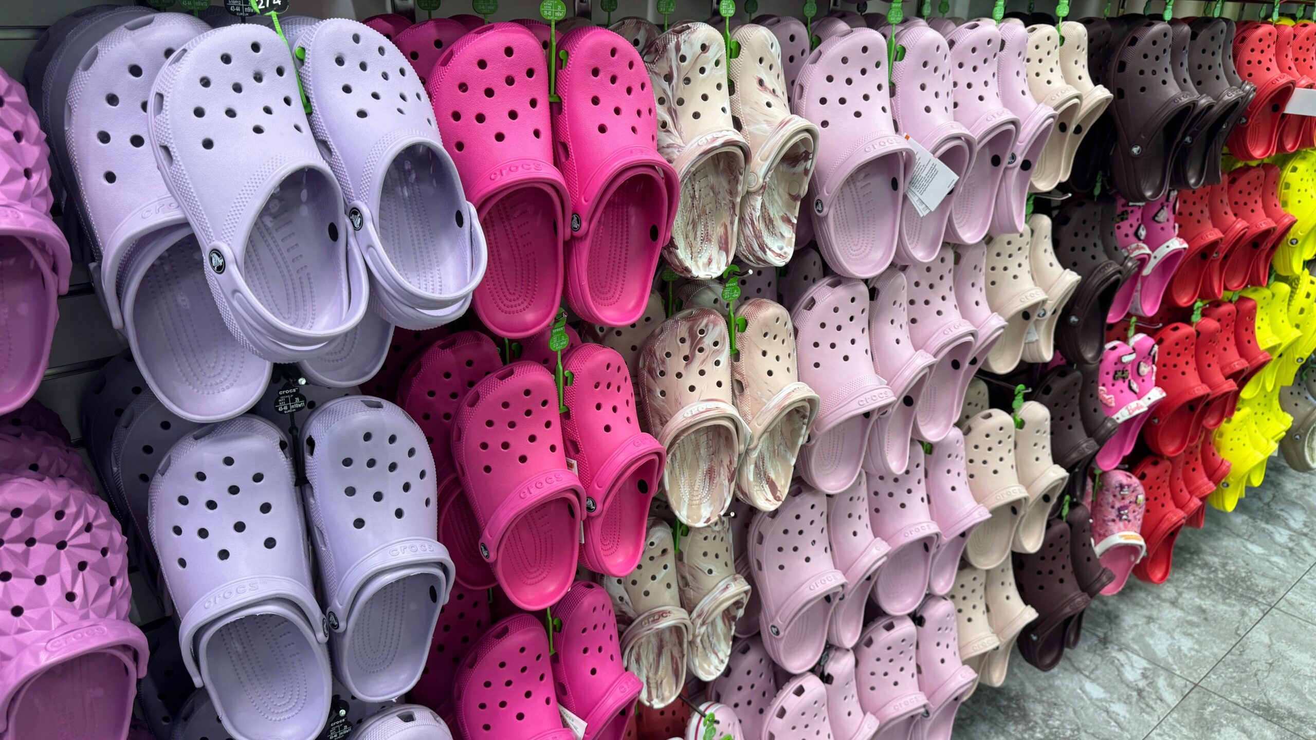 crocs-wall-display-pink-neutrals display of crocs hanging on wall with multiple color options