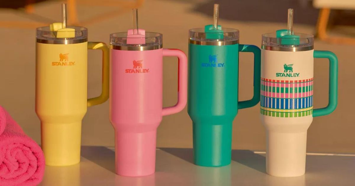 four Stanley tumblers in a row next to beach towels