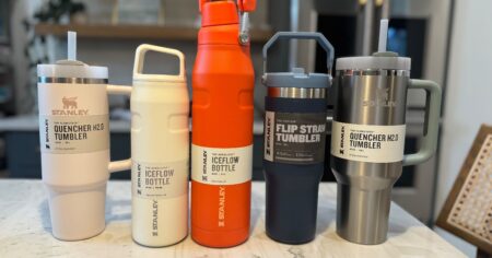 Five different Stanley brand water bottles sitting on a counter including the Stanley Quencher Tumbler