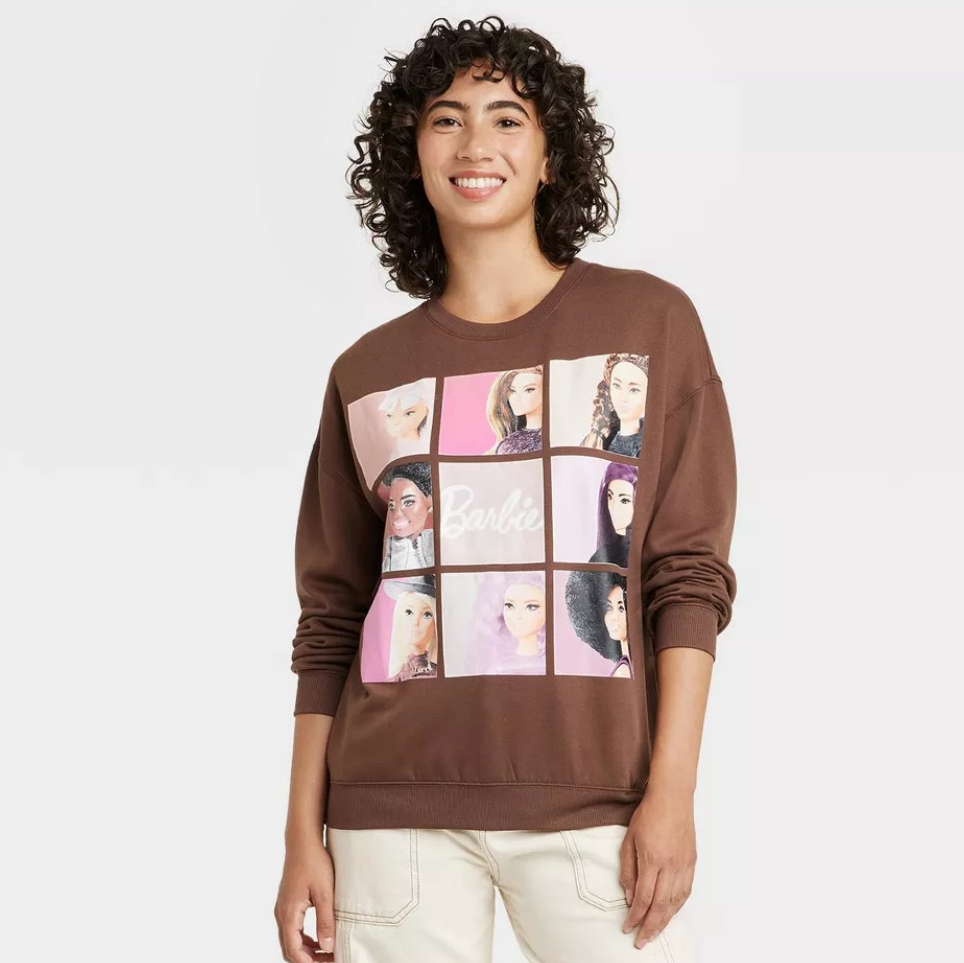 woman wearing a brown sweatshirt with images of Barbie's on it