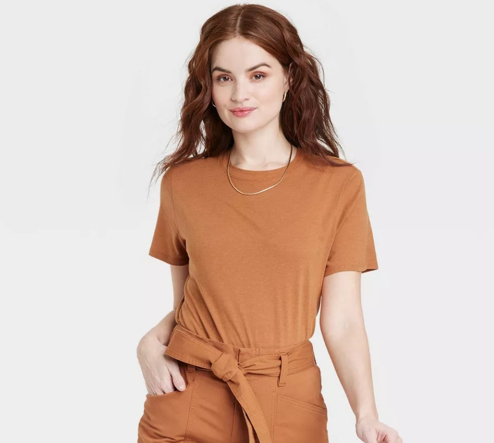 woman smiling at the camera and wearing a brown shirt