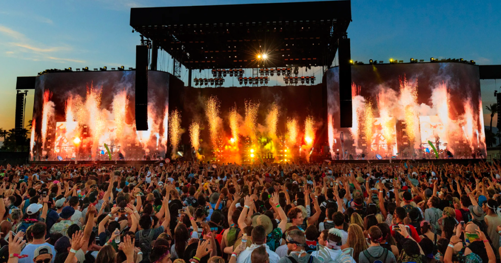 large crowd of people at a Coachella concert with fireworks coming from the stage