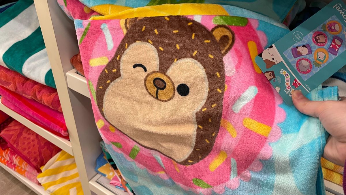hand holding a beach towel with a Squishmallow design on it