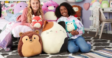girls sitting by a bed holding Squishmallows