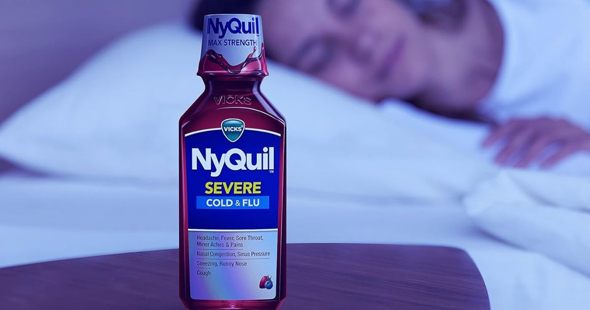 bottle of Nyquil on a nightstand with a woman sleeping in the background