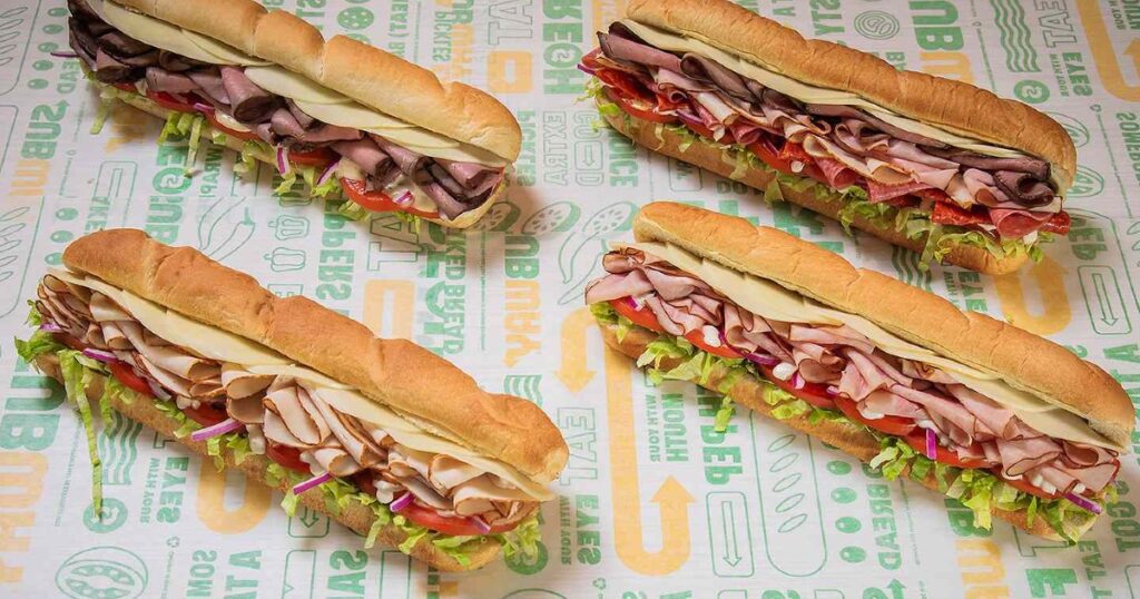 four subway footlong sandwiches on subway brand paper