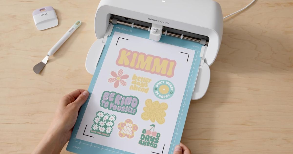 hand holding a Cricut mat with sticker paper on it