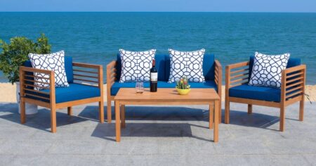 two chairs, table, and a loveseat on a patio overlooking water