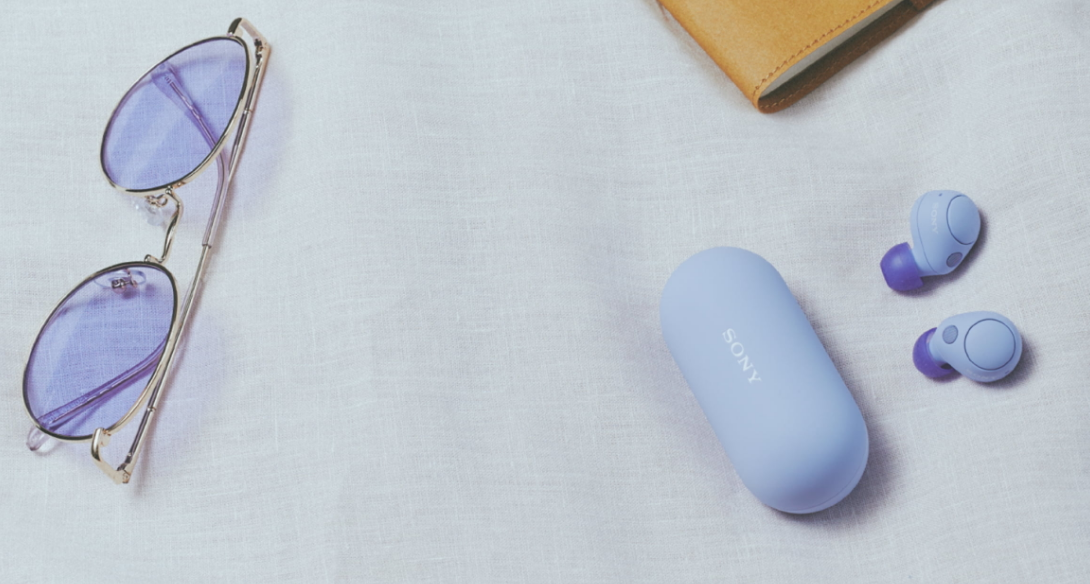 Noise Canceling Truly Wireless Earbuds earbuds next to a case and a pair of sunglasses