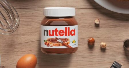 jar of Nutella with hazelnuts by it