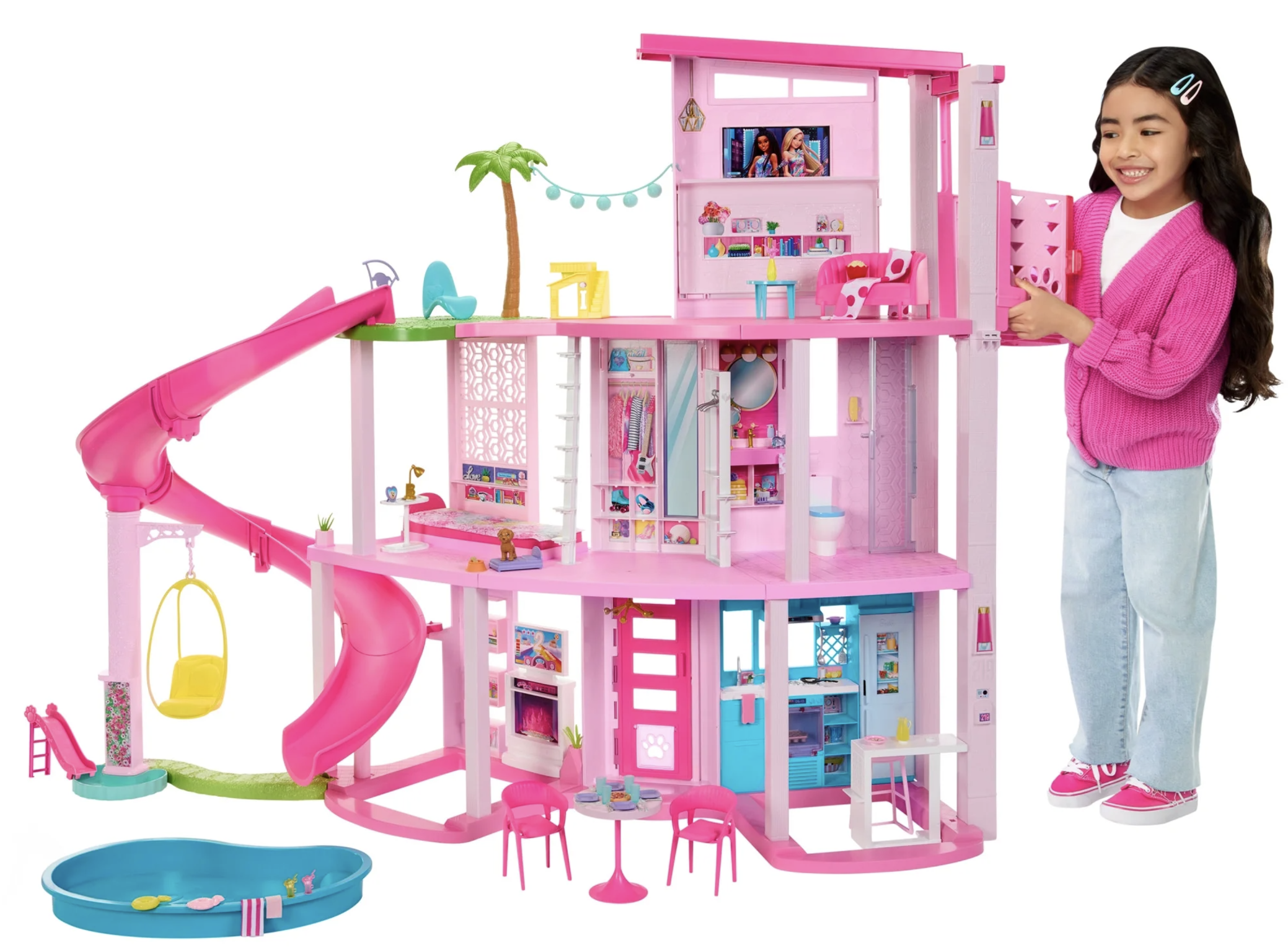 girl standing next to a Barbie dreamhouse